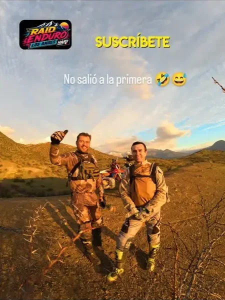 Dos pilotos de pie junto a la moto cuando ya cae la tarde sobre el cerro.