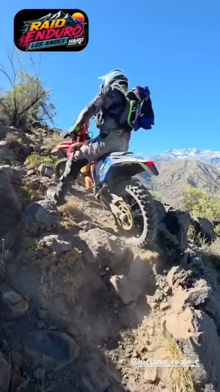 Piloto subiendo un peldaño de roca con la moto cargada al límite.